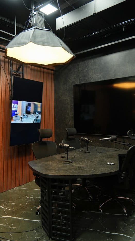 Estúdio da HLS com mesa de gravação, painel de madeira e telas de cenário
