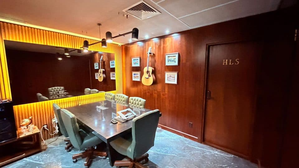 Sala de reunião com mesa longa, iluminação quente e poltronas